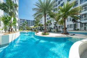 a swimming pool with palm trees and buildings at Capri Residence Bangtao in Bang Tao Beach
