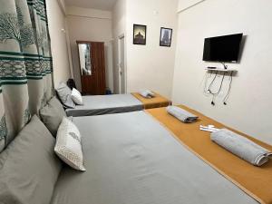 a room with two beds and a flat screen tv at Dhruvanish Grand in Sringeri