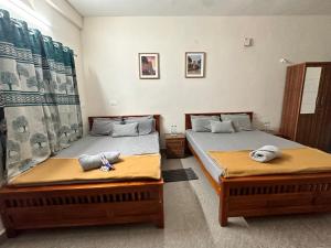 two beds in a hotel room with towels on them at Dhruvanish Grand in Sringeri