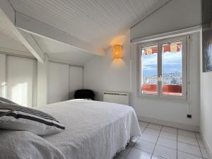 a white bedroom with a bed and a window at Bigarena in Hendaye