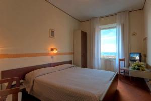 una camera da letto con un letto, una finestra e una televisione di Hotel Giardinetto a Loreto