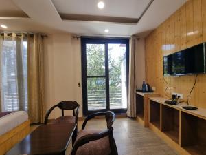 a room with a table and chairs and a television at Nomad Uber Hotel - Near Mall Road Dalhousie in Dalhousie