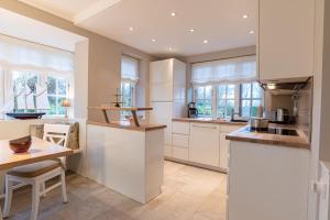 a kitchen with white cabinets and a wooden table at Friesenliebe in Borgsum