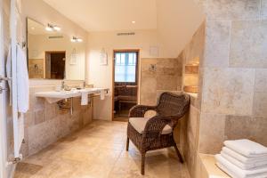 a bathroom with a wicker chair and a sink at Friesenliebe in Borgsum +27 photos