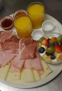 a plate of food with meat and fruit and two glasses of juice at Pension Paradise Slowakia in Pastovce