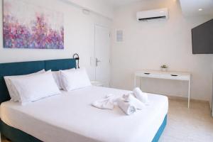 a bedroom with a white bed with towels on it at Notos Boutique Apartments 3 with Private Jacuzzi in Heraklio