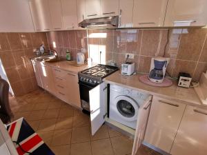 a kitchen with a stove and a washing machine at Elisa Summerland Apartment in Mamaia +36 photos