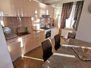 a kitchen with white cabinets and a table with chairs at Elisa Summerland Apartment in Mamaia