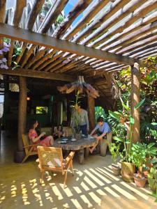 a group of people sitting around a table under a wooden roof at SURF N SUN - Arugam Bay in Arugam Bay