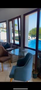 a living room with chairs and a glass table and windows at Studio moderne soleil piscine wifi à cabonegro in Tétouan