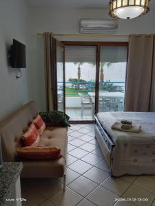 a bedroom with a bed and a couch and a balcony at Studio moderne soleil piscine wifi à cabonegro in Tétouan +13 photos