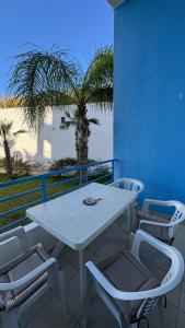 a white table and chairs on a balcony with a palm tree at Studio moderne soleil piscine wifi à cabonegro in Tétouan