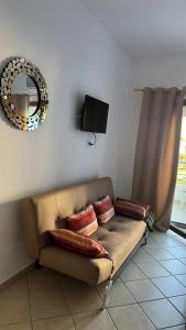 a couch sitting in a living room with a mirror at Studio moderne soleil piscine wifi à cabonegro in Tétouan
