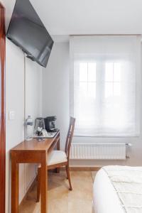 a bedroom with a desk with a chair and a television at Habitaciones Guriezo in El Puente +34 photos