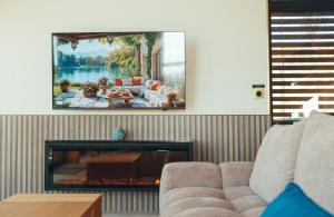 a living room with a couch and a tv above a fireplace at Ostara Ecolodge in Saint-Mards-en-Othe