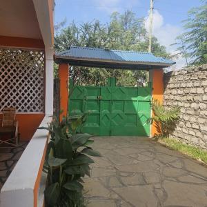 a green gate in a house with a stone wall at Orange apartment 1 in Watamu