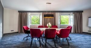 a dining room with a table and red chairs at PLAZA INN Schmöker-Hof in Norderstedt