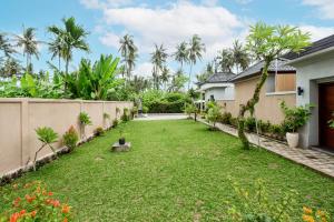 a yard of a house with grass and trees at Merta Luwih Villa in Tanah Lot
