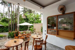 a restaurant with wooden tables and chairs and large windows at Merta Luwih Villa in Tanah Lot