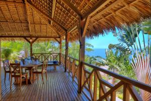 a porch with a table and chairs and the ocean at Manja Kely Lodge - Nosy Komba Island in Nosy Be
