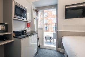 a room with a bed and a kitchen with a microwave at MSK The Whiteley in London