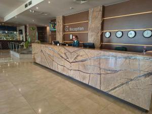 a woman sitting at a reception desk in a restaurant at Hotel Golden Tulip Varna in Varna City