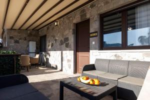 a patio with a couch and a bowl of fruit on a table at Adonis Resort & Spa in Egina