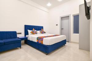 a bedroom with a blue bed and a blue chair at FabHotel Saraca Inn in Indore