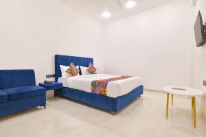 a bedroom with a blue bed and a blue chair at FabHotel Saraca Inn in Indore