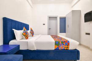a bedroom with a large bed with a blue headboard at FabHotel Saraca Inn in Indore