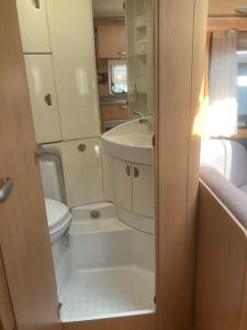 a small bathroom with a toilet and a sink at Mietwohnwagen S1 am Flussufer in Wienhausen