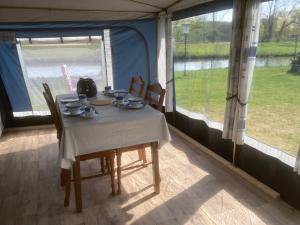 a table in a tent with a view of a river at Mietwohnwagen S1 am Flussufer in Wienhausen +12 photos