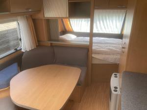 a small room with a table and a bed at Mietwohnwagen S1 am Flussufer in Wienhausen