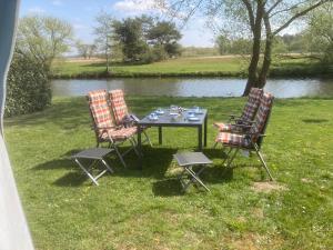 a table and four chairs sitting next to a river at Mietwohnwagen S1 am Flussufer in Wienhausen