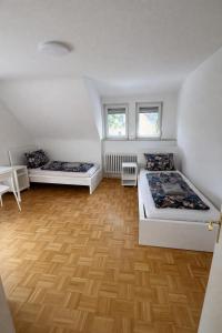 two beds in a room with wooden floors and windows at Pension am Heckenacker in Rothenburg ob der Tauber