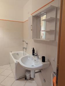 a white bathroom with a sink and a bath tub at Il Centro Apartments 2 in Salsomaggiore Terme +12 photos