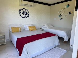 two beds in a room with white walls at Pousada Mangue Seco in Itaúnas
