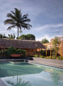 a swimming pool with a thatched building and a palm tree at Punarjeevani Ayurvedic Heritage in Vythiri