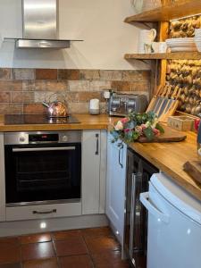 a kitchen with a stove and a counter top at Pet Friendly, Border Cottage, Norfolk in Briston