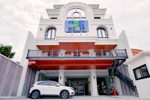 a white car parked in front of a building at Front One Hotel Mesir Surabaya in Surabaya