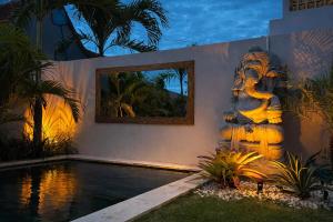 a house with a swimming pool with a statue next to it at 2BR Villa Surrounded by Rice Fields Cemagi in Cemagi