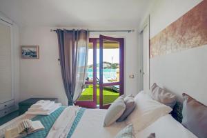 a bedroom with a bed and a door to a balcony at Aquaemaris Apartment in La Maddalena