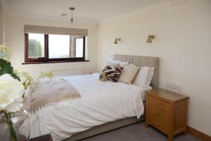 a bedroom with a white bed with a wooden night stand at Dukes Well in Congleton