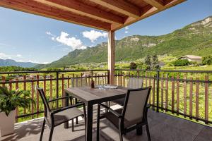 a table and chairs on a balcony with a view of mountains at Prälatenhof Wine & Apartments in Caldaro