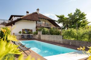 a villa with a swimming pool in front of a house at Prälatenhof Wine & Apartments in Caldaro