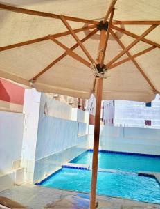 a swimming pool with an umbrella next to it at Lady Queen Apartment in Marsa Alam City