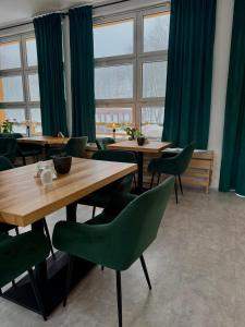 a restaurant with green chairs and tables and windows at Lázně Meziboří in Meziboři