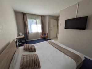 a bedroom with a bed and a flat screen tv at Hotel L'Océane Angers Parc Expo in Saint-Sylvain-dʼAnjou