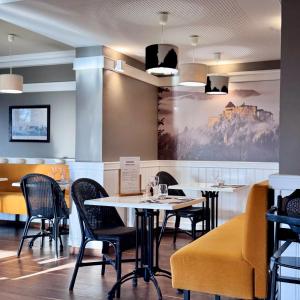 a restaurant with tables and chairs and a painting on the wall at ibis Dole Sud Choisey in Dole