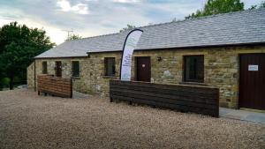a stone building with two benches in front of it at 3 Peaks Bunkroom in Settle